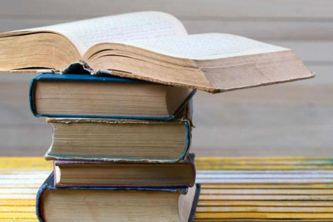 Image of a stack of five books, the book on top is open, for an article on natural wine glossary.