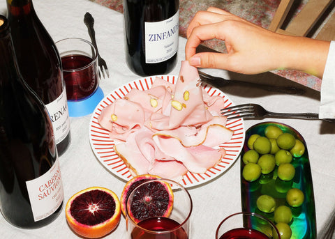 Wine and charcuterie with oranges on a table.