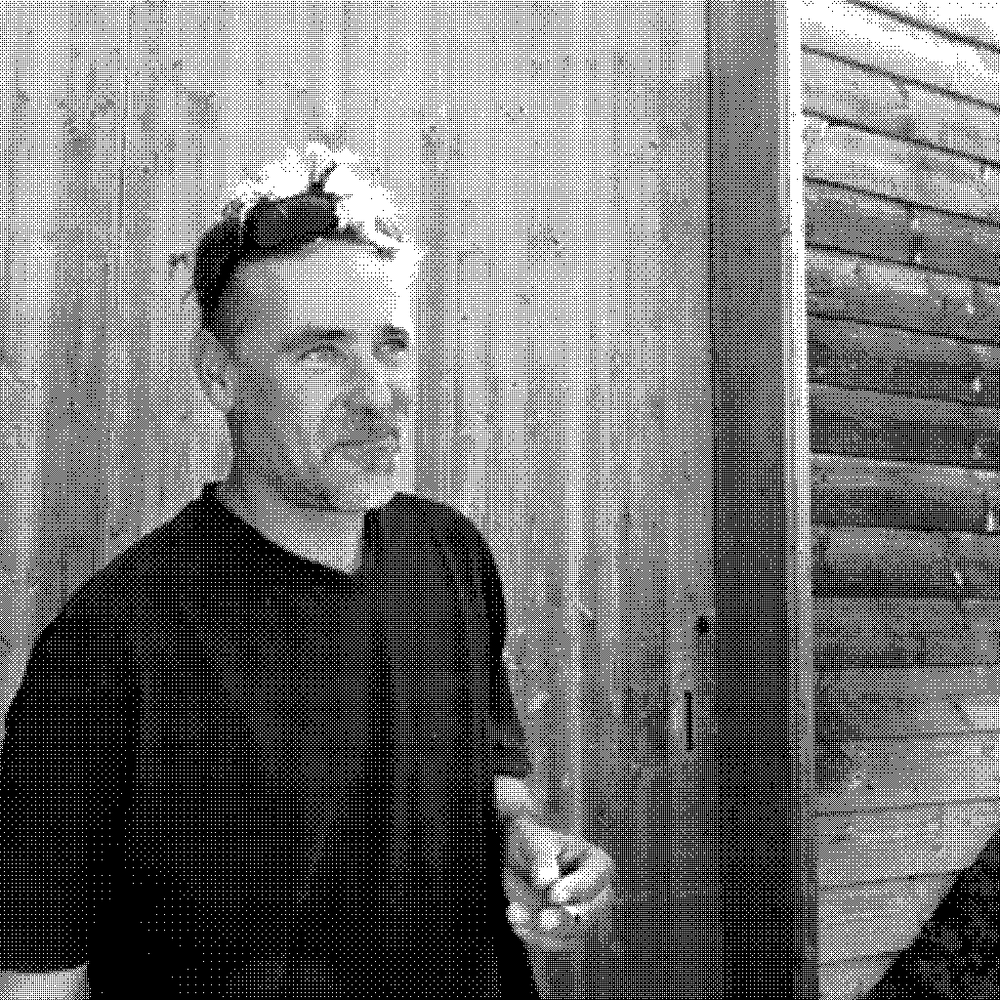 Andrea Calek, natural wine producer, holding a glass of wine outside his cellar in the Ardeche, France