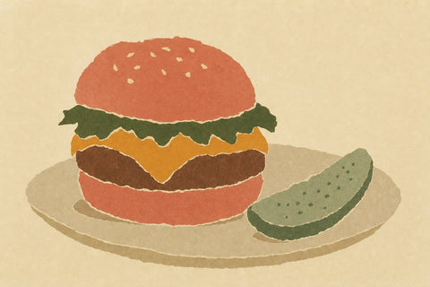 Paper-cutout illustration of a cheeseburger on a plate next to a pickle