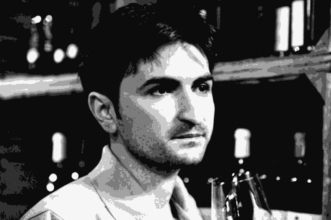 Winemaker Massimiliano Croci holding a glass of his sparkling wine in the cellar