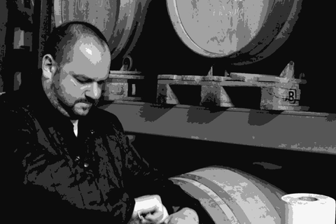 Thomas Teibert of Domaine de l'Horizon bottling wine in his cellar in front of oak barrels