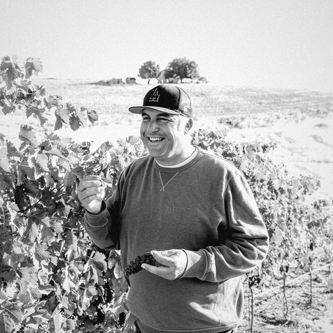 Andrew Jones of Field Recordings with grapes in a Central Coast vineyard, black and white