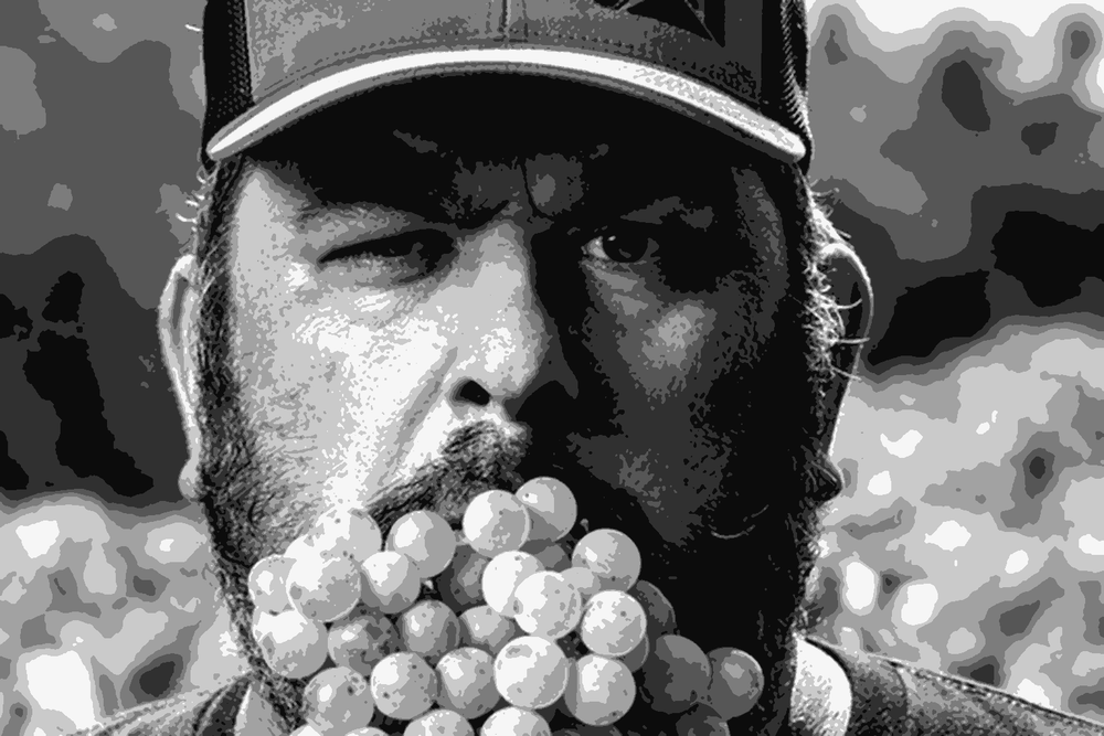 Fredi Torres in his Catalonian vineyard holding a cluster of grapes