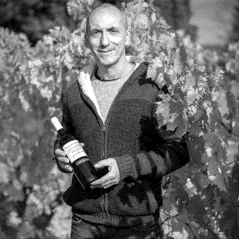 Fabio de Ambrogi, natural wine producer of Fattoria di Gratena, holding a bottle in his vineyard near Arezzo in Tuscany, Italy