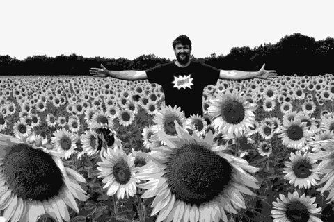 Laurent Cazottes standing in a sunflower field, smiling with arms outstretched