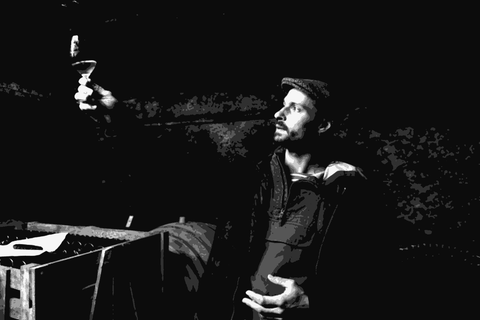 Baptiste Cousin in a stone cellar holding a glass of wine up to examine it