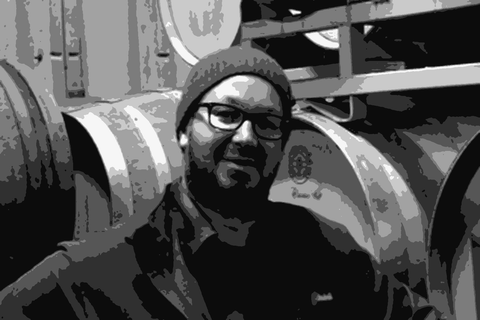 Mike Roth standing in a barrel room at Coquelicot Estate, smiling at the camera