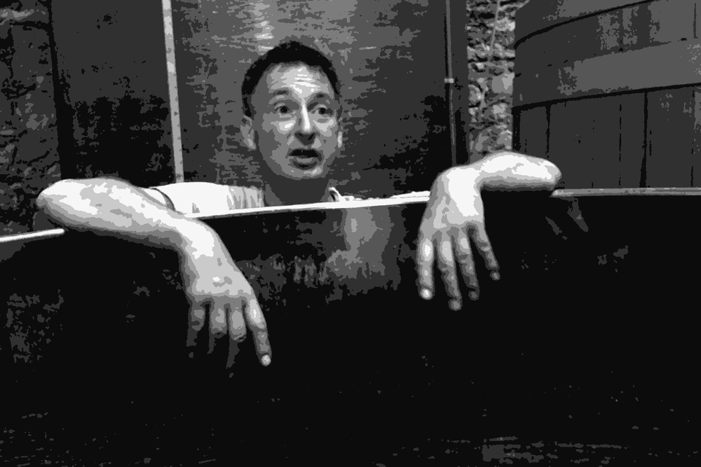Axel Prufer of Le Temps des Cerises peering over a fermentation vessel in his Languedoc cellar