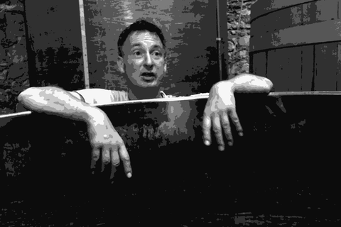 Axel Prufer of Le Temps des Cerises peering over a fermentation vessel in his Languedoc cellar