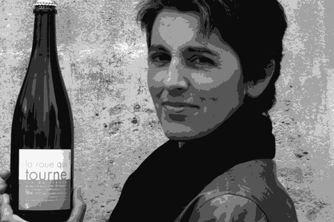 Marie Thibault holding a bottle of her La Roue Qui Tourne pétillant naturel in front of a stone wall, Azay-le-Rideau, Loire Valley