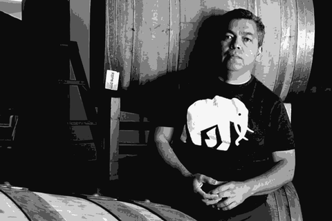 Noel Diaz, founder of Purity Wine, standing among barrels in his Richmond, California winery