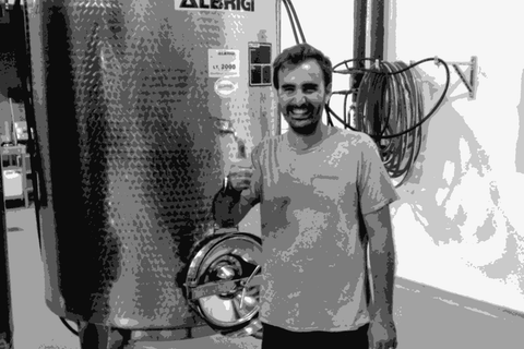 Sauro Maule standing next to a stainless steel tank in his winery, giving a thumbs up