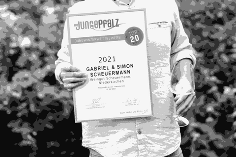 Gabriel Scheuermann standing outdoors holding a Junge Pfalz Top 20 award certificate, smiling
