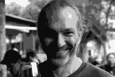Alex Schulkin of The Other Right holding a glass of red wine and smiling