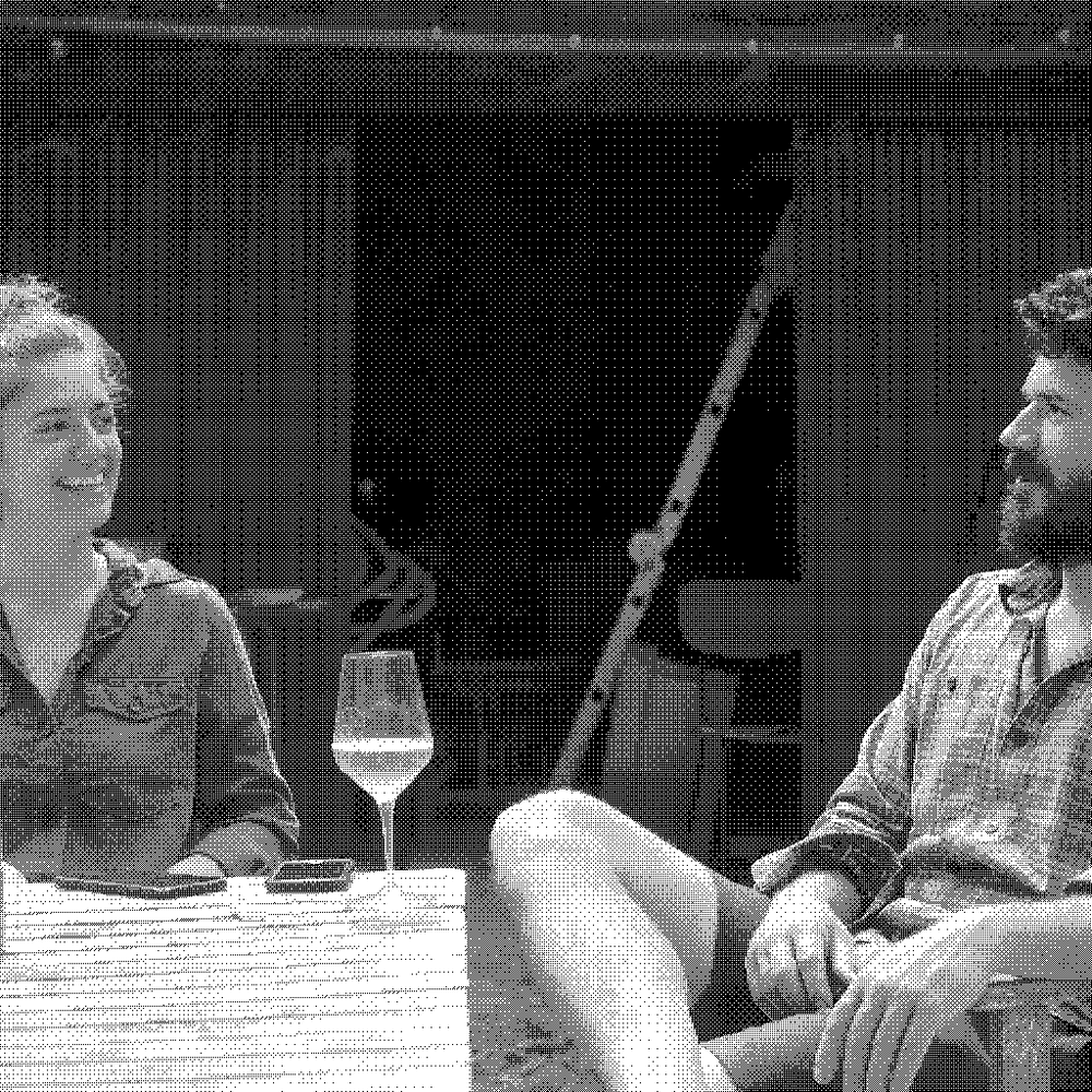 Antoine Le Court and Julia Naar of Les Valseuses, natural wine producer in the Jura, France, seated outdoors with a glass of their rose