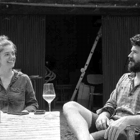 Antoine Le Court and Julia Naar of Les Valseuses, natural wine producer in the Jura, France, seated outdoors with a glass of their rose
