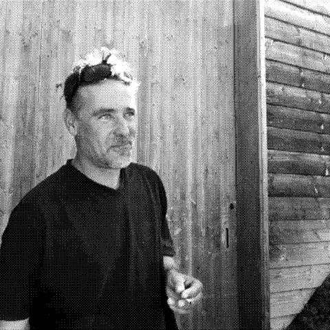 Andrea Calek, natural wine producer, holding a glass of wine outside his cellar in the Ardeche, France