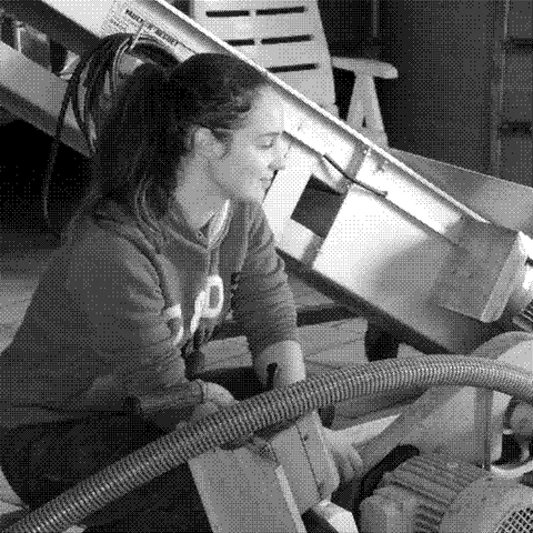 Barbara Lebled, natural wine producer, kneeling at the press in her cellar in the Loire Valley, France