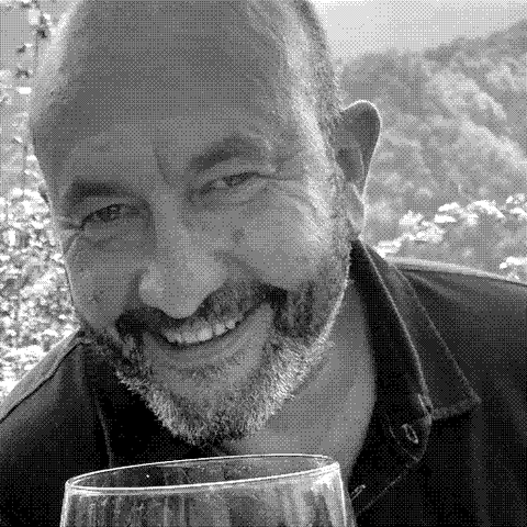 Andrea Scovero, natural wine producer, smiling with a glass of red wine in his vineyard in Piedmont, Italy